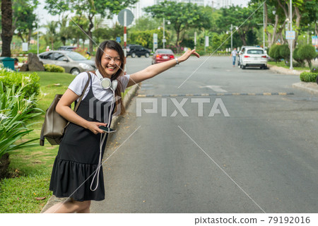Smiling woman waiting and hailing taxi Smiling woman waiting and hailing taxi 79192016