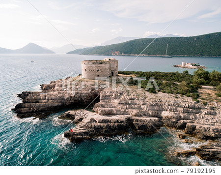 Man and woman in love stand embracing on the rocky seashore near Arza fortress 79192195