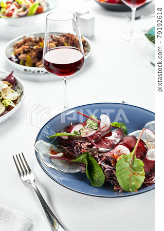 Festive table with beef jerky appetizer, brisaola with lettuce leaves on the festive table with wine and light naperons. Festive table with beef jerky appetizer, brisaola with lettuce leaves on the festive table with wine and light naperons. 79192618