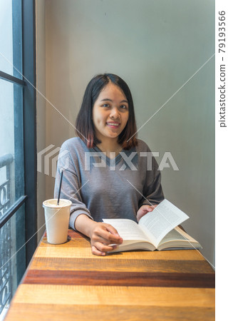 Smiling girl enjoys her day with book and coffee Smiling girl enjoys her day with book and coffee 79193566