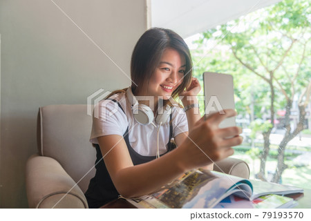 Cute Asian woman smiling and taking a selfie Cute Asian woman smiling and taking a selfie 79193570