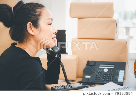 Asian beautiful woman Receiving order by phone and notebooks in selling products online, Working at home the technology to buy and sell of online, preparing products for delivery to customers 79193894
