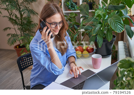 Smiling young lady typing on laptop at home 79194526