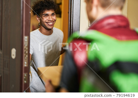 Its pizza time. Young guy looking happy while meeting courier with pizza box, spending time at home alone 79194619