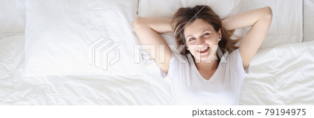 Smiling happy woman lies on white bed Smiling happy woman lies on white bed 79194975