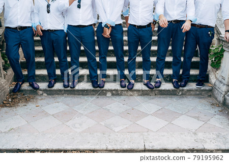 Seven groom's best men in identical blue trousers and shoes stand on the stairs, close-up  79195962