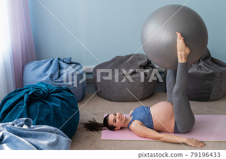 Pregnant european woman performs exercises with fitness ball. Expectant mother is doing yoga in the 3rd trimester. Girl in the classroom in preparation for childbirth. Pregnant european woman performs exercises with fitness ball. Expectant mother is doing yoga in the 3rd trimester. Girl in the classroom in preparation for childbirth. 79196433