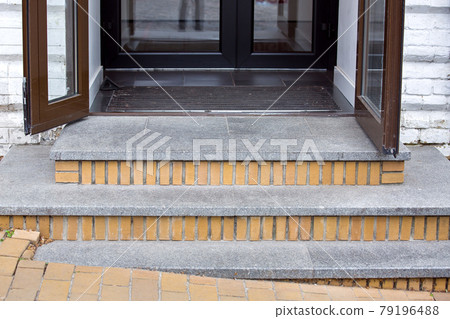 threshold with granite steps of a brick house with brown iron doors with glass and foot mat close-up, nobody. threshold with granite steps of a brick house with brown iron doors with glass and foot mat close-up, nobody. 79196488