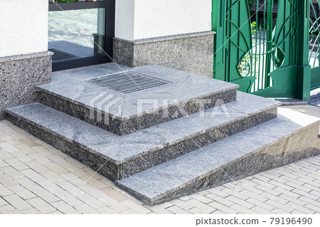 granite gray porch step with a foot mat at the entrance to the central door made of glass modern architecture office style close-up with green gate, nobody. 79196490