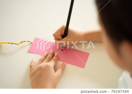 A child writing a wish on a strip of paper A child writing a wish on a strip of paper 79197384