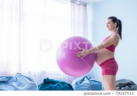 A pregnant woman in sportswear is doing gymnastics for pregnant women. The girl is engaged in fitness with a ball for expectant mothers. Last trimester. A pregnant woman in sportswear is doing gymnastics for pregnant women. The girl is engaged in fitness with a ball for expectant mothers. Last trimester. 79197533