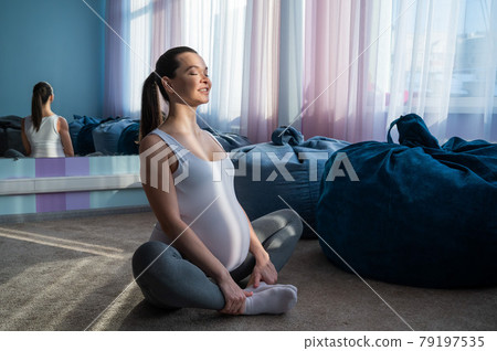 Happy pregnant woman practice yoga. A girl in the third trimester leads Pilates. Classes to prepare for childbirth. Waiting for the baby. Appeasement. 79197535