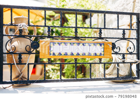 Blank sign on a forged metal fence against the background of clay jugs 79198048