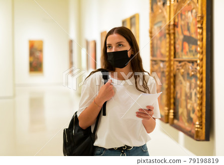 Young girl in a protective mask visits an exhibition of paintings in a museum Young girl in a protective mask visits an exhibition of paintings in a museum 79198819