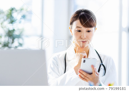 Female doctor looking at a smartphone in the hospital 79199181