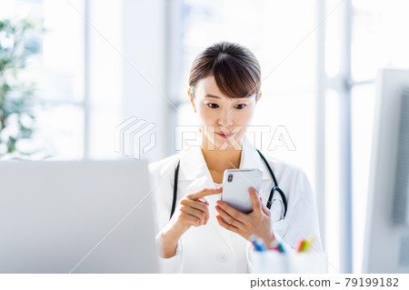 Female doctor looking at a smartphone in the hospital 79199182