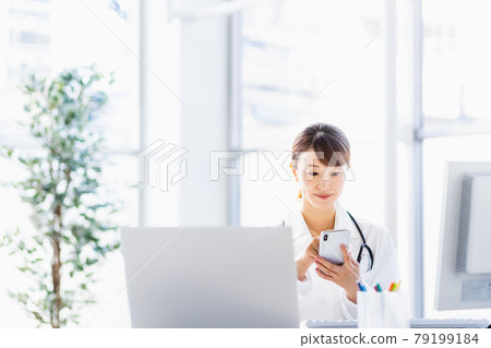Female doctor looking at a smartphone in the hospital Female doctor looking at a smartphone in the hospital 79199184