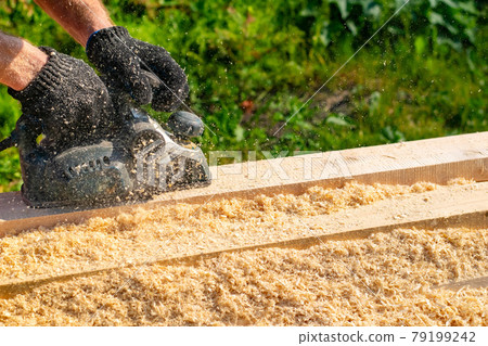 the hands of a person, a worker, a carpenter hold an electric plane 79199242