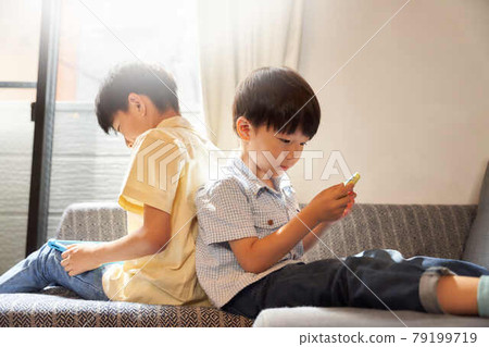 兩個男孩盯著客廳的屏幕 79199719