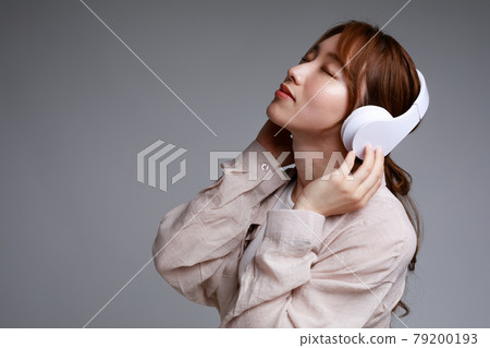Young woman listening to music with headphones 79200193