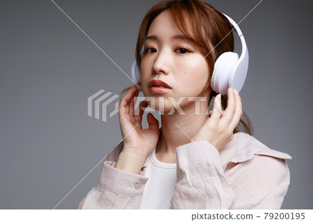Young woman listening to music with headphones Young woman listening to music with headphones 79200195