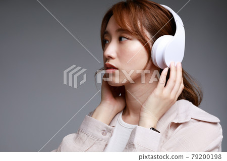 Young woman listening to music with headphones Young woman listening to music with headphones 79200198