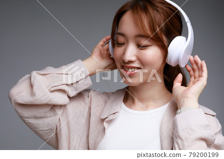Young woman listening to music with headphones Young woman listening to music with headphones 79200199