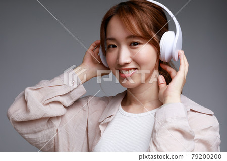 Young woman listening to music with headphones Young woman listening to music with headphones 79200200
