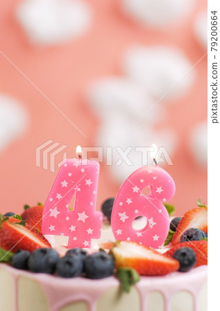 Birthday cake number 46. Beautiful pink candle in cake on pink background with white clouds. Close-up and vertical Birthday cake number 46. Beautiful pink candle in cake on pink background with white clouds. Close-up and vertical 79200664