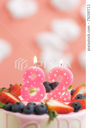 Birthday cake number 82. Beautiful pink candle in cake on pink background with white clouds. Close-up and vertical Birthday cake number 82. Beautiful pink candle in cake on pink background with white clouds. Close-up and vertical 79200711