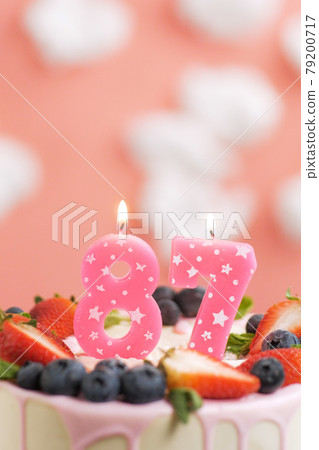 Birthday cake number 87. Beautiful pink candle in cake on pink background with white clouds. Close-up and vertical 79200717