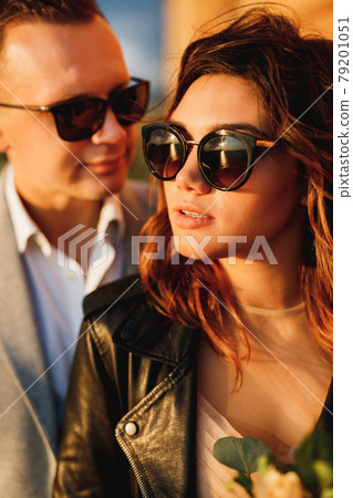 Portrait of bride in sunglasses and a black leather jacket on the background of groom 79201051
