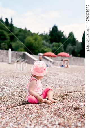 Little girl in panama sits on the beach, turning back Little girl in panama sits on the beach, turning back 79201052