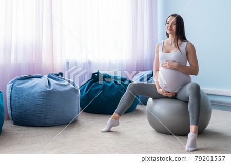 Beautiful european woman doing pregnant exercises. Expectant mother is doing exercises with a fitness sword. Yoga for expectant mothers. 79201557