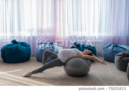 Beautiful european woman doing pregnant exercises. Expectant mother is doing exercises with a fitness sword. Yoga for expectant mothers. Beautiful european woman doing pregnant exercises. Expectant mother is doing exercises with a fitness sword. Yoga for expectant mothers. 79201613