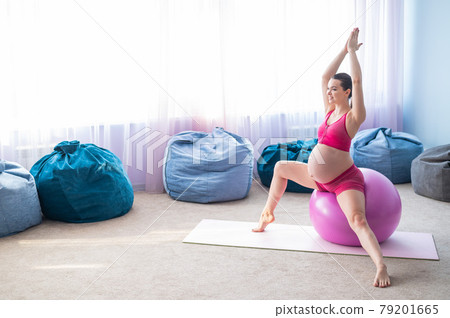 Beautiful pregnant woman doing exercises on a fitness ball. Expectant mother in the last trimester doing yoga. Beautiful pregnant woman doing exercises on a fitness ball. Expectant mother in the last trimester doing yoga. 79201665