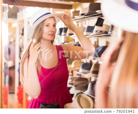 woman try on lady's hat and looking in mirror at outlet store woman try on lady's hat and looking in mirror at outlet store 79201941