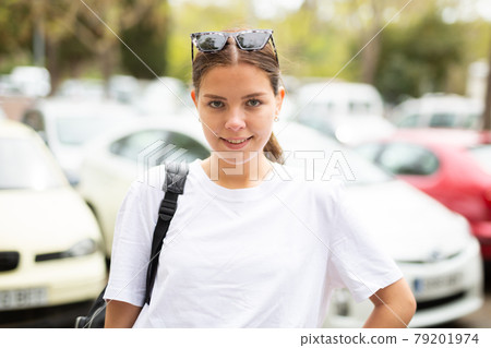 Portrait of a positive girl standing on the street near cars Portrait of a positive girl standing on the street near cars 79201974