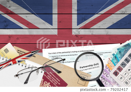 English Tax form sa104 Partnership from HM revenue and customs lies on table with office items. HMRC paperwork and tax paying process in United Kingdom 79202417