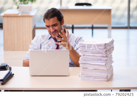 Young male employee unhappy with excessive work in the office Young male employee unhappy with excessive work in the office 79202425