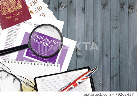 English violet guide Applying for a passport lies on table with office items. UK passport paperwork English violet guide Applying for a passport lies on table with office items. UK passport paperwork 79202437