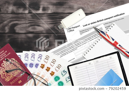 English form LS01 Lost or stolen british passport notification from HM passport office lies on table with office items. UK passport paperwork 79202459