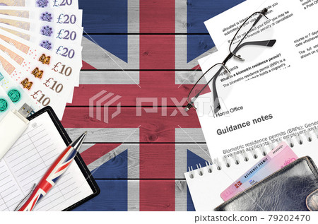 English form BRP with guidance notes to applying biometric residence permit card from UK visas and immigration services lies on table with office items. UK residence permit paperwork English form BRP with guidance notes to applying biometric residence permit card from UK visas and immigration services lies on table with office items. UK residence permit paperwork 79202470
