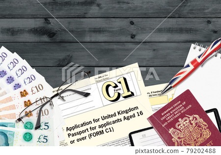 English form C1 Application for United Kingdom passport for applicants aged 16 or over lies on table with office items. UK passport paperwork English form C1 Application for United Kingdom passport for applicants aged 16 or over lies on table with office items. UK passport paperwork 79202488