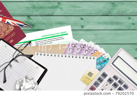 English form 64-8 Authorising your agent from HM revenue and customs lies on table with office items. HMRC paperwork and tax paying process in United Kingdom 79202570