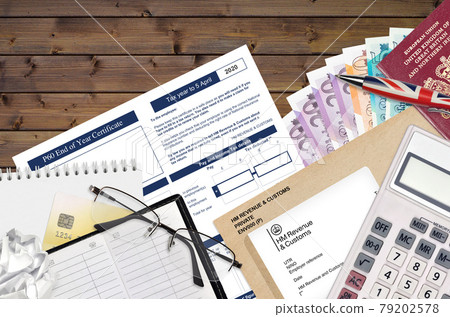 English Tax form P60 End of year certificate by HM revenue and customs lies on table with office items. HMRC paperwork and tax paying process in United Kingdom 79202578