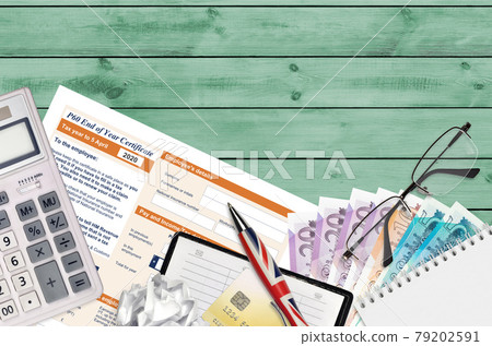 English Tax form P60 End of year certificate by HM revenue and customs lies on table with office items. HMRC paperwork and tax paying process in United Kingdom English Tax form P60 End of year certificate by HM revenue and customs lies on table with office items. HMRC paperwork and tax paying process in United Kingdom 79202591