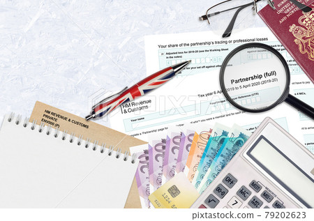 English Tax form sa104 Partnership from HM revenue and customs lies on table with office items. HMRC paperwork and tax paying process in United Kingdom English Tax form sa104 Partnership from HM revenue and customs lies on table with office items. HMRC paperwork and tax paying process in United Kingdom 79202623