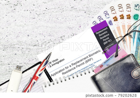 English form BRP RC Application for a replacement biometric residence permit card from UK visas and immigration services lies on table with office items. UK residence permit paperwork 79202628