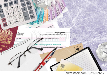 English Tax form sa102 Employment by HM revenue and customs lies on table with office items. HMRC paperwork and tax paying process in United Kingdom 79202647
